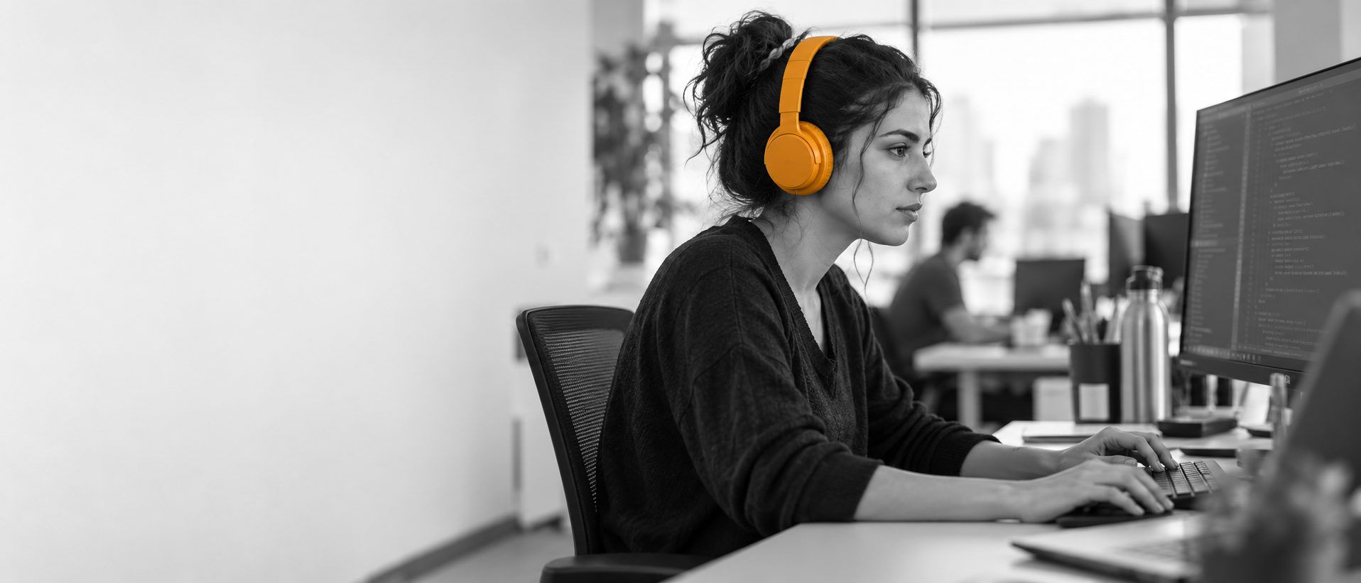 A developer at a monitor wearing orange headphones, placeholder photograph